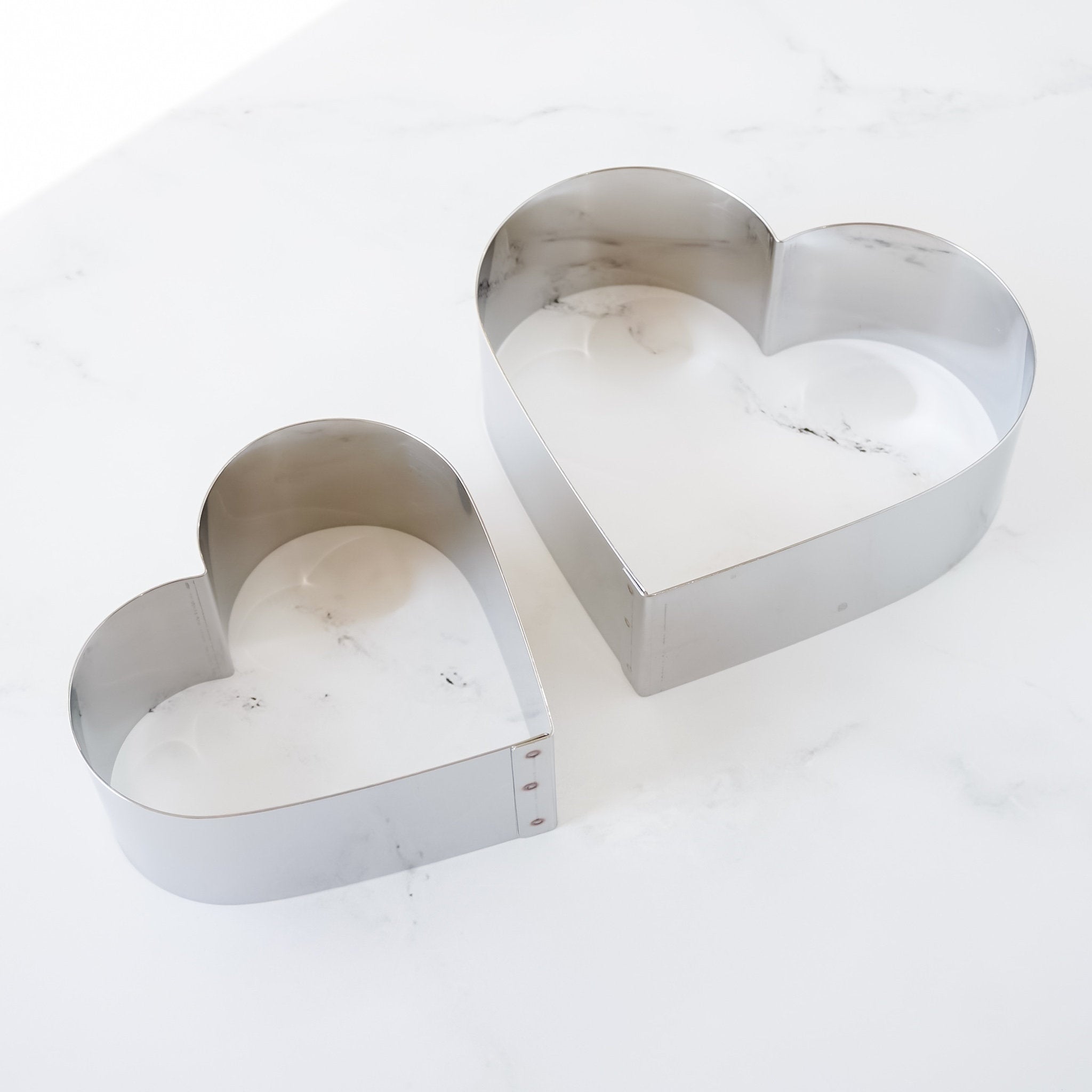 Two heart-shaped cake rings made of stainless steel, displayed on a white surface.