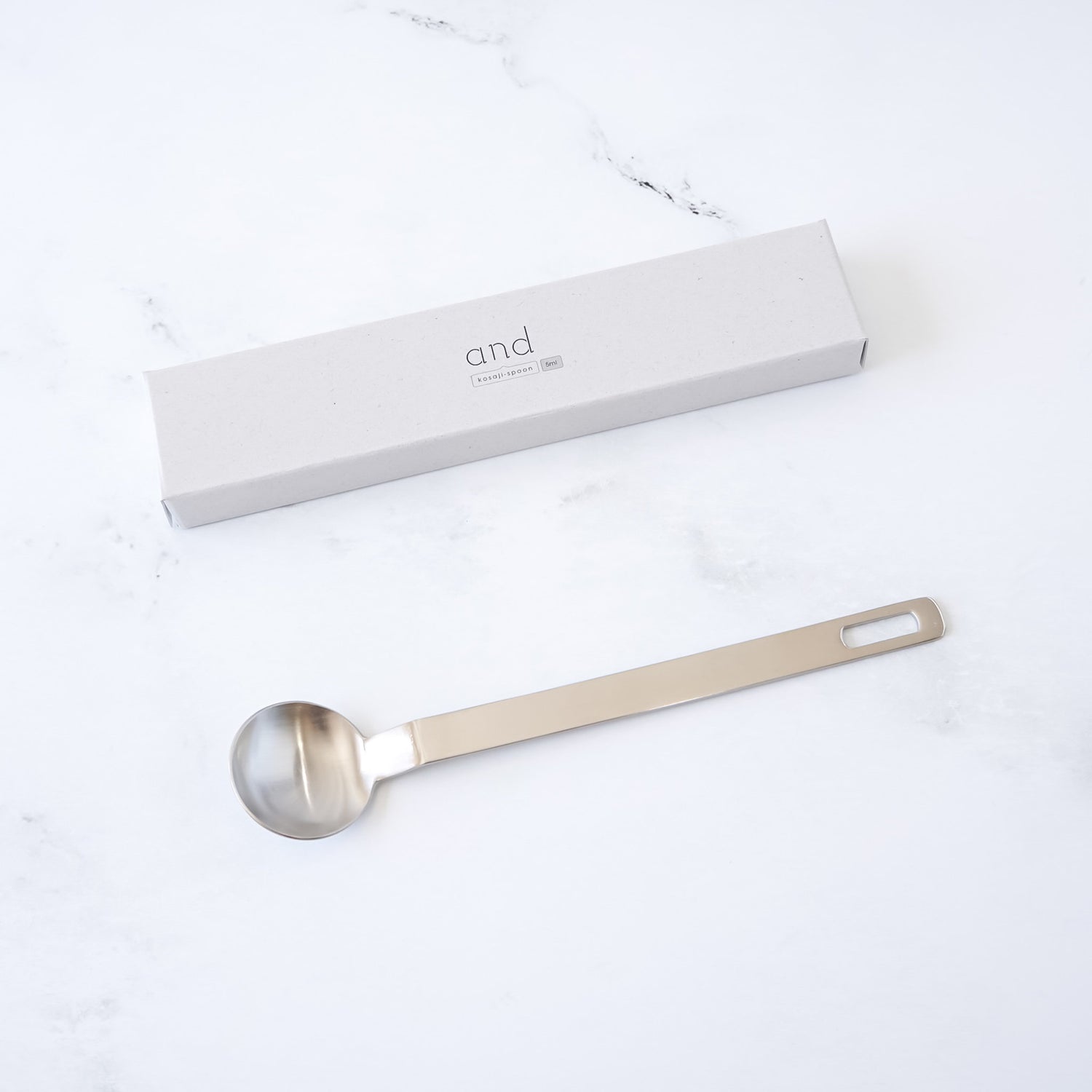 Stainless steel teaspoon with a branded box on a white surface