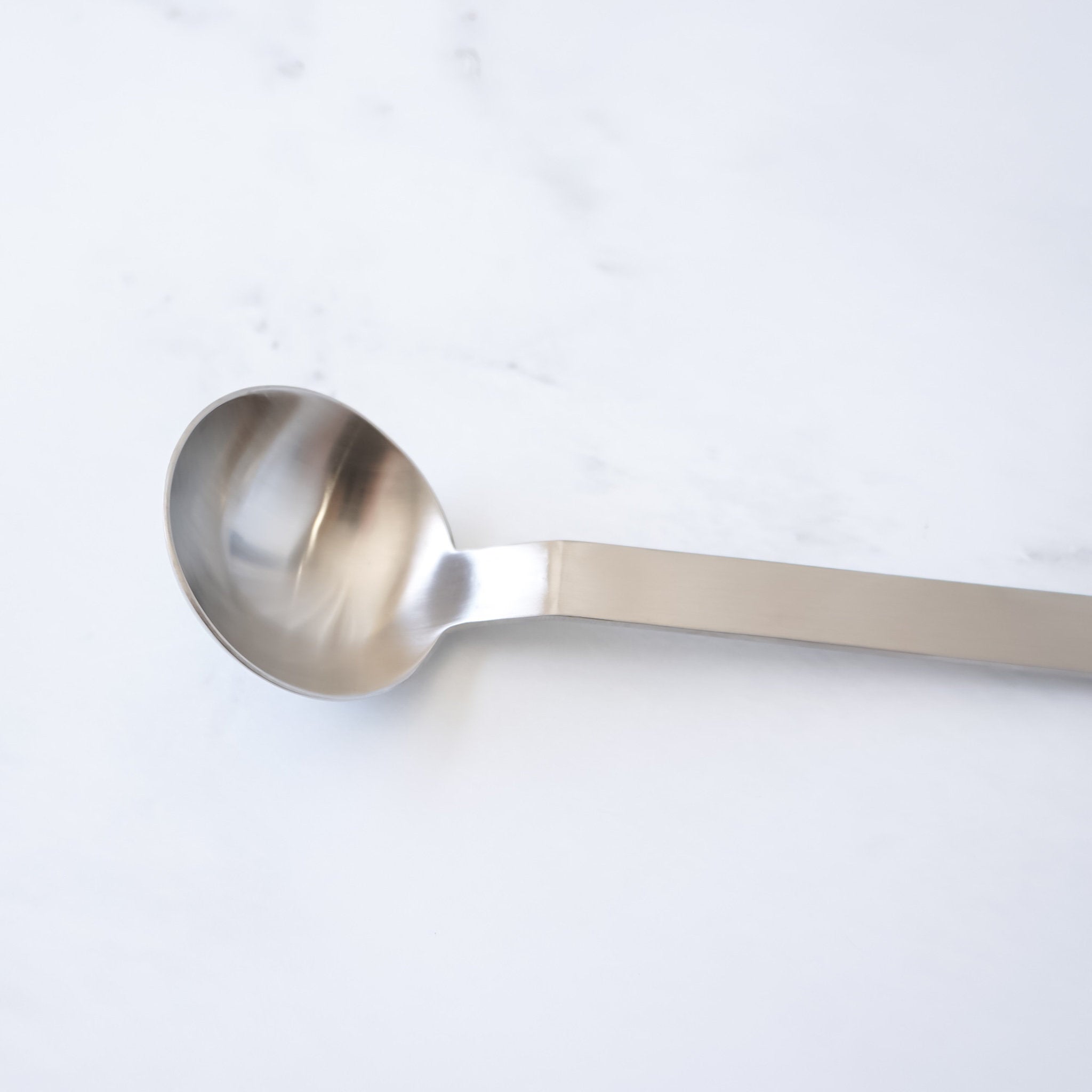 stainless steel measuring spoon on a light gray background
