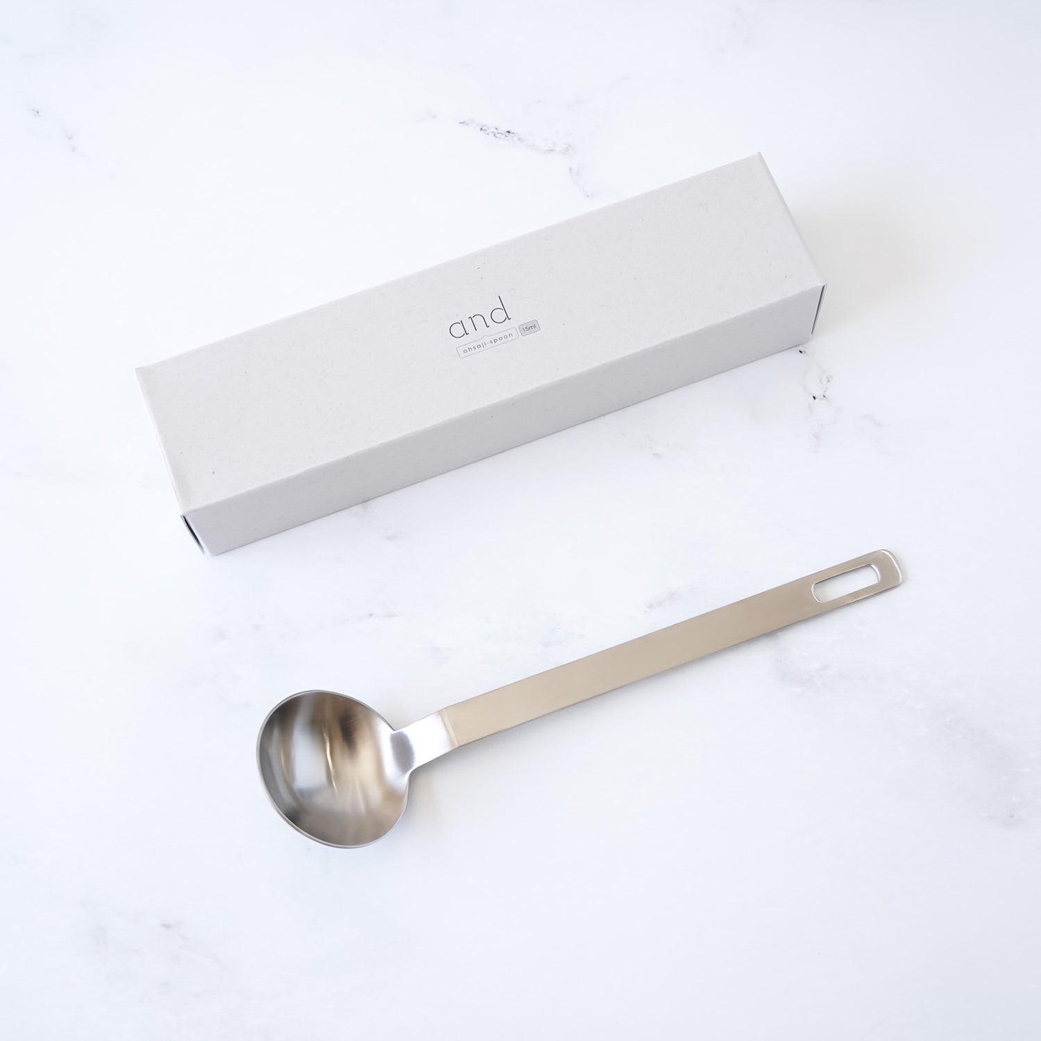 Stainless steel tablespoon with a branded box on a white background