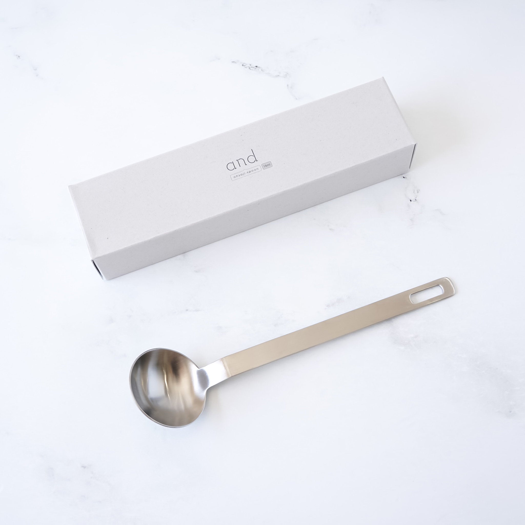 Stainless steel tablespoon with a branded box on a white background