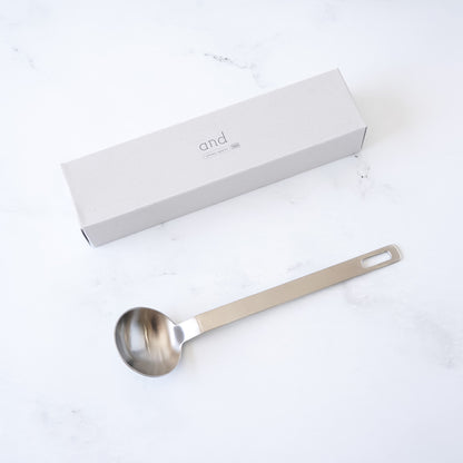 Stainless steel tablespoon with a branded box on a white background