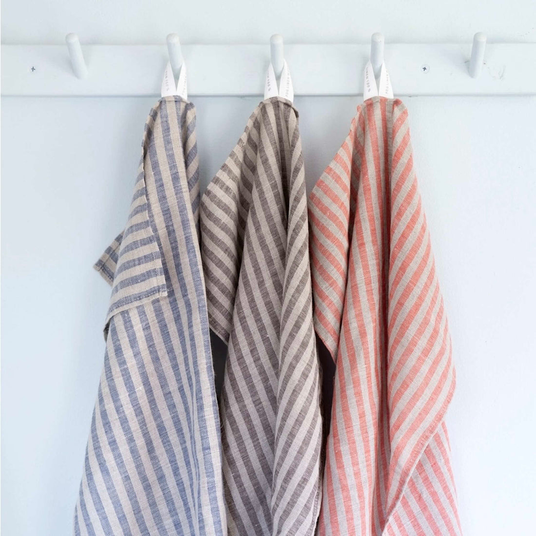 Three striped towels hanging on a rack against a white background