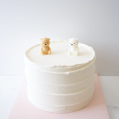 White cake with two small bear candles on a white background