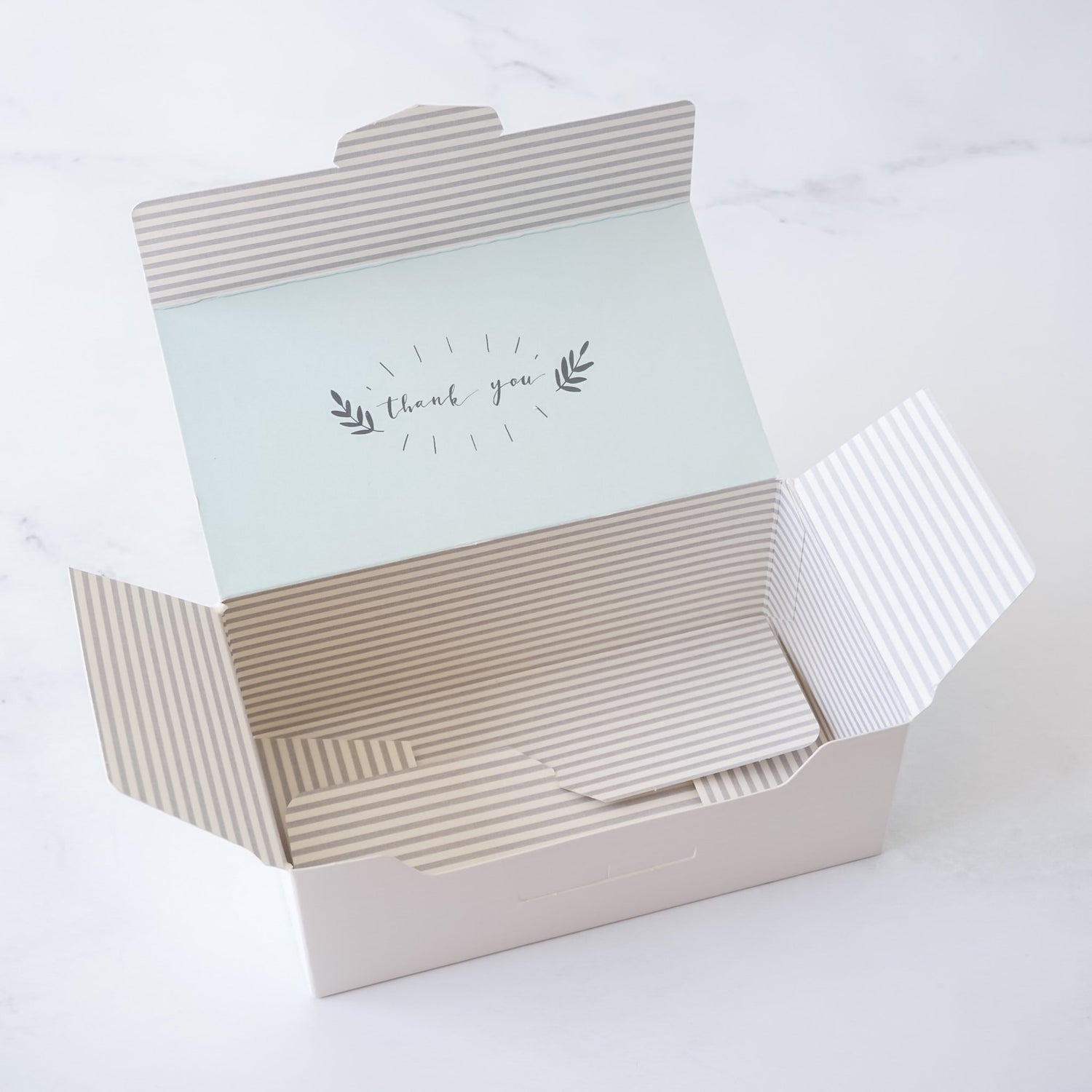 Open gift box with light gray striped pattern inside on a white background