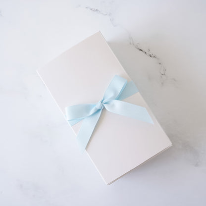 White cookie box with a light blue ribbon on a marble surface