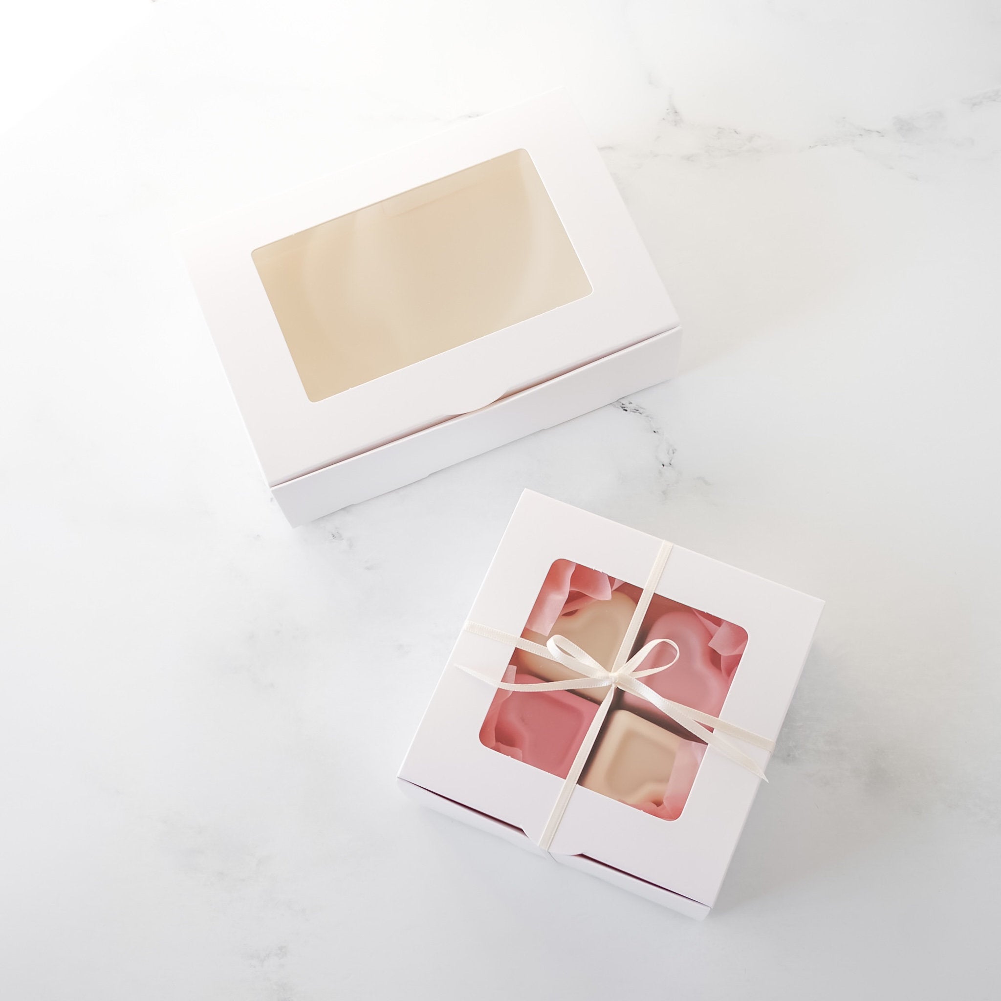 Four chocolate cookies in white boxes on a light surface