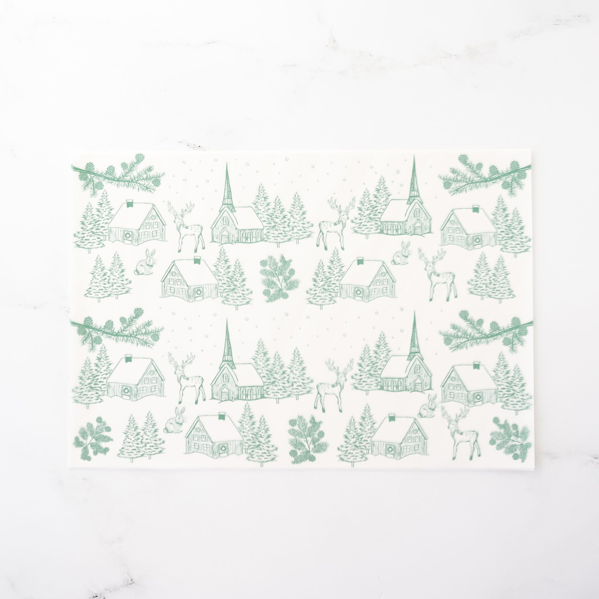 Semi-sheer deli paper with a winter village scene, including snowy houses, reindeer, rabbits, and trees, printed in classic green. 